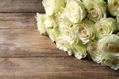 Luxury bouquet of fresh roses on wooden table, closeup. Space for text