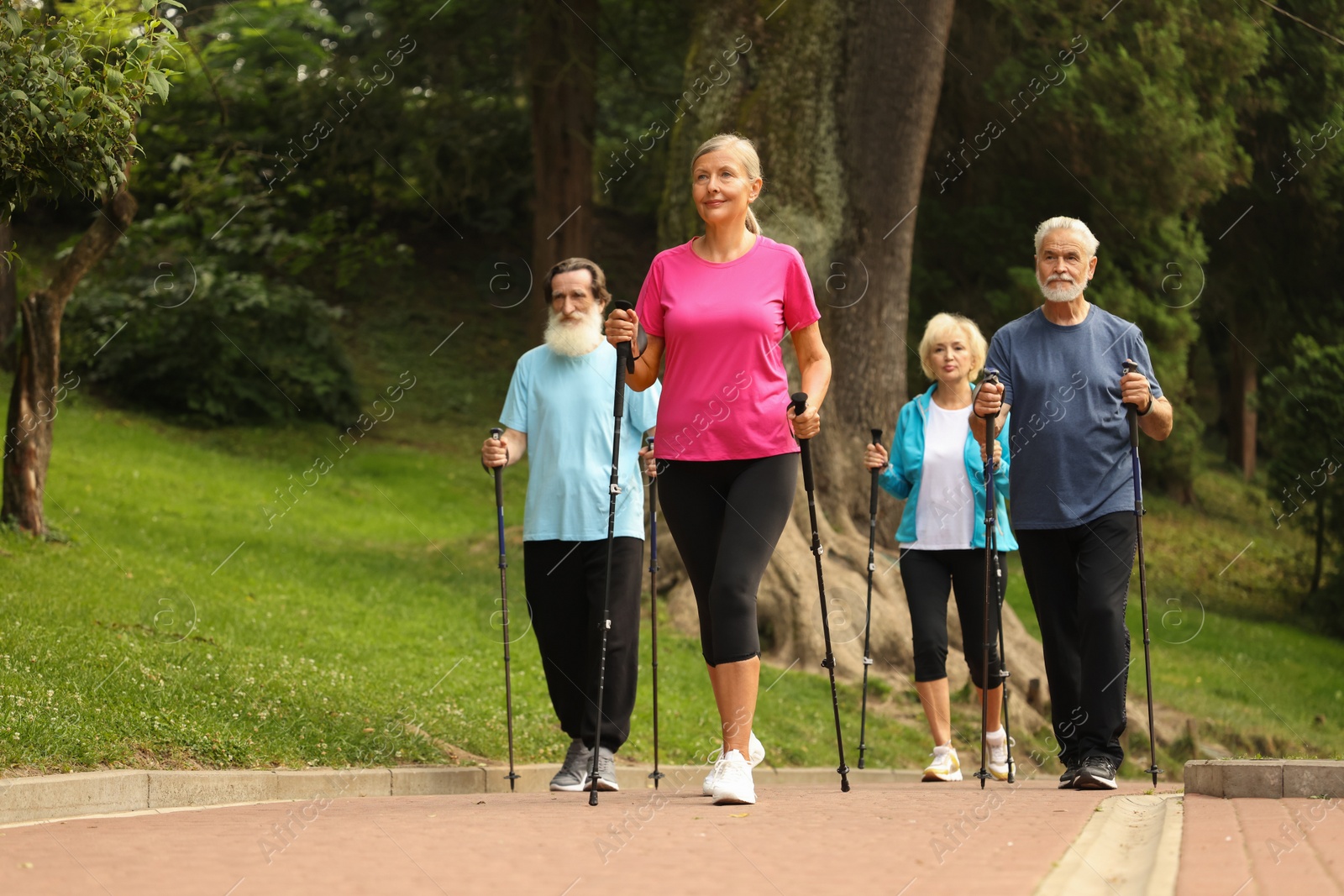 Photo of Group of senior people performing Nordic walking outdoors. Low angle view