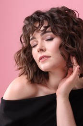 Portrait of beautiful young woman with wavy hairstyle on pink background