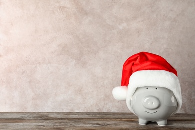 Photo of Cute piggy bank with Santa hat on table. Space for text