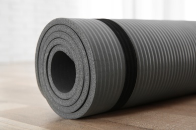 Photo of Rolled grey yoga mat on floor indoors