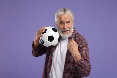 Senior sports fan with soccer ball on purple background