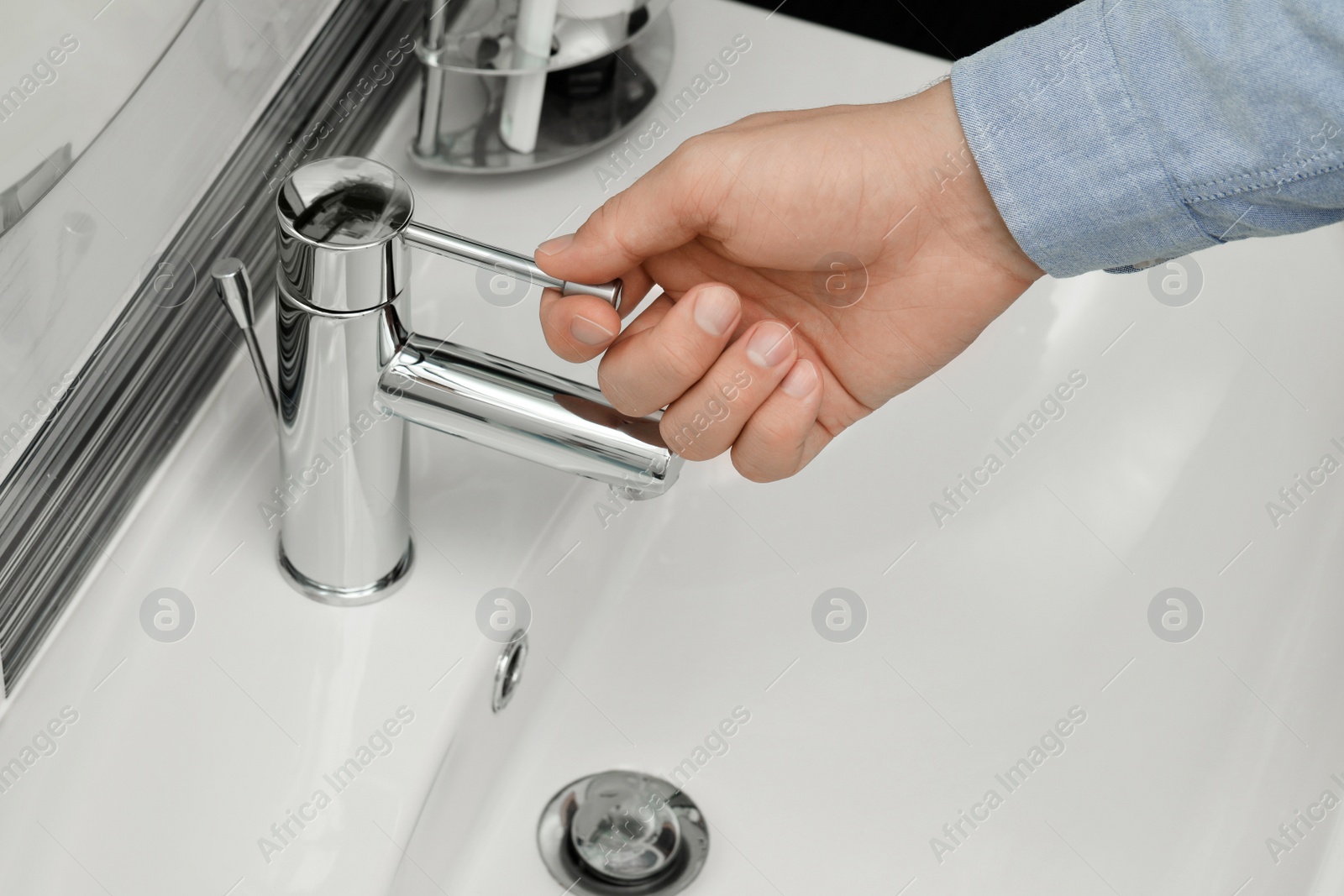 Photo of Man using water tap in bathroom, closeup