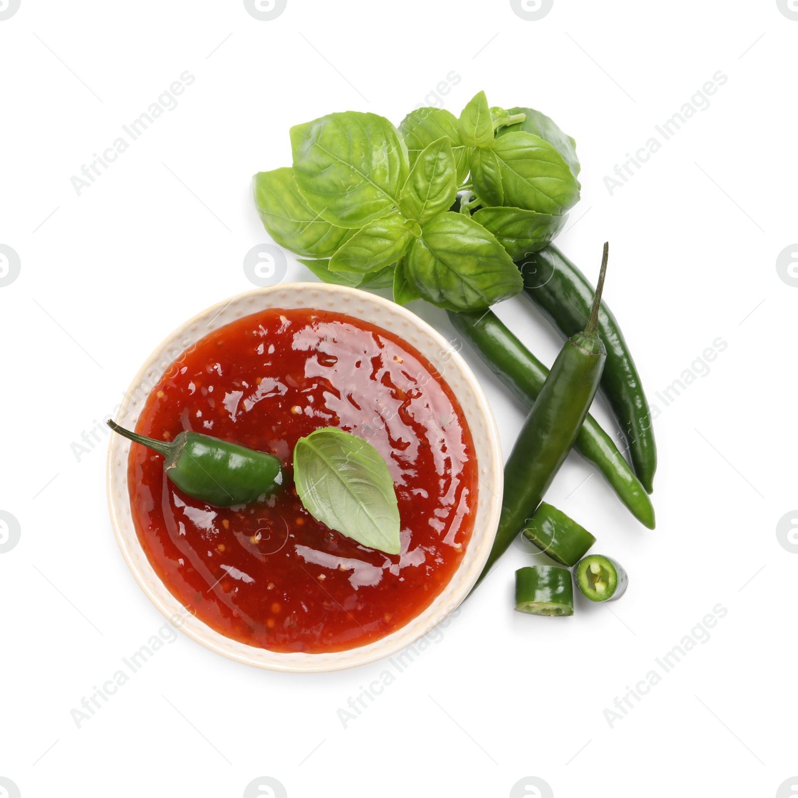 Photo of Spicy chili sauce and ingredients on white background, top view