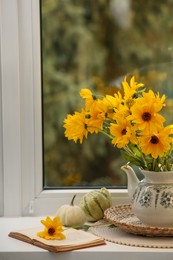 Photo of Composition with beautiful flowers, pumpkins and book on windowsill, space for text. Autumn atmosphere