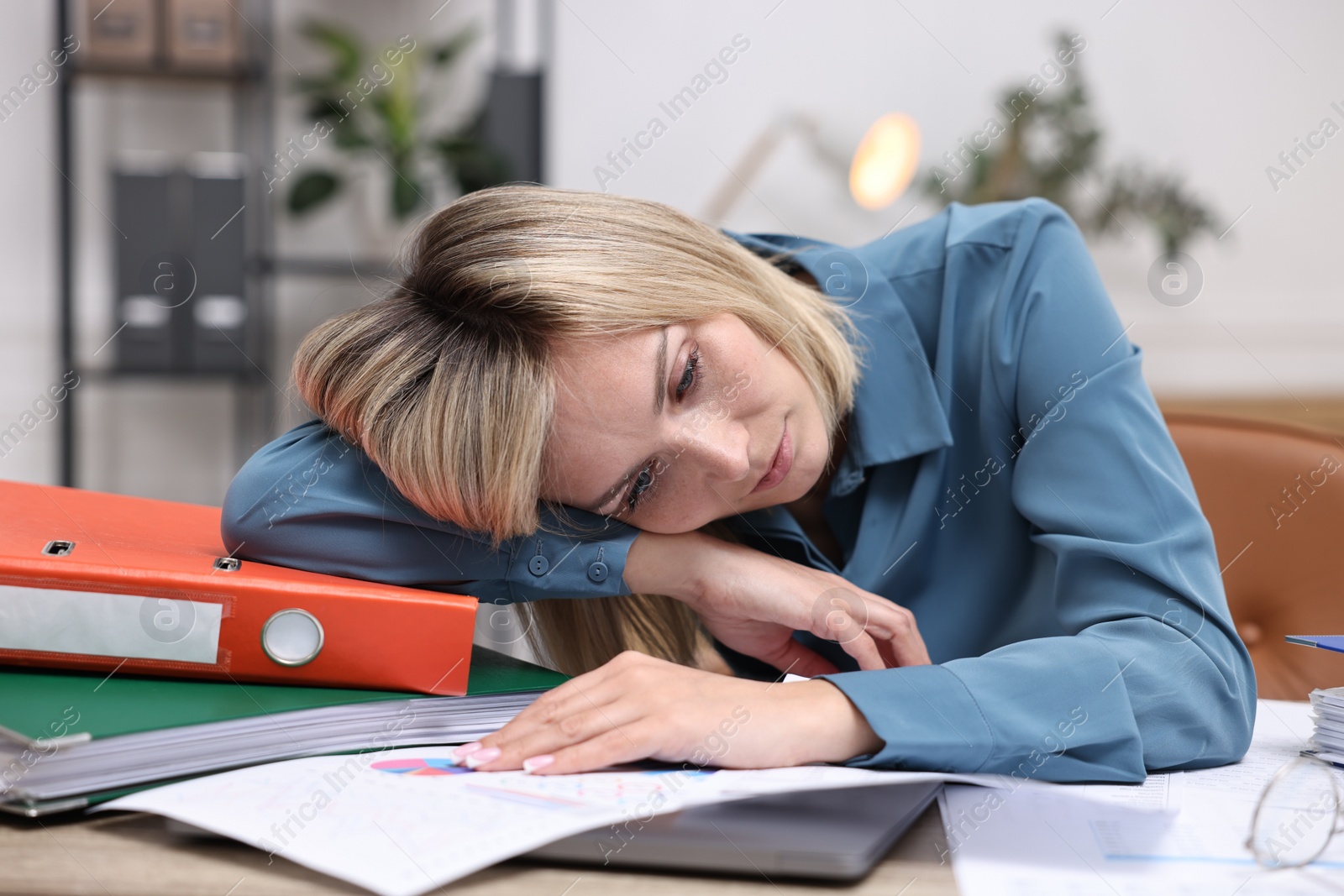 Photo of Overwhelmed woman sitting at table with documents in office