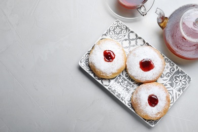 Photo of Hanukkah food doughnuts with jelly and sugar powder served on grey table, flat lay. Space for text