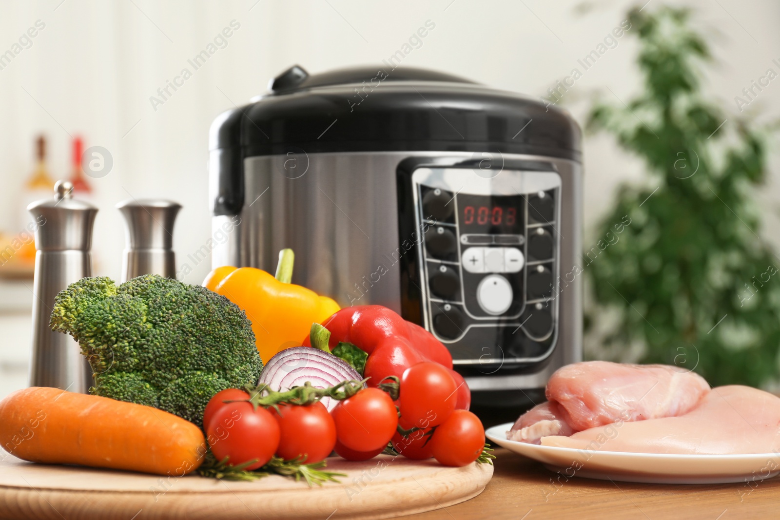 Photo of Modern multi cooker and ingredients on wooden table in kitchen