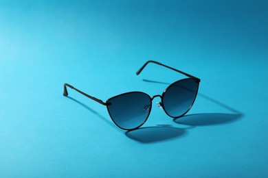 Photo of Sunglasses on light blue background. Stylish accessory