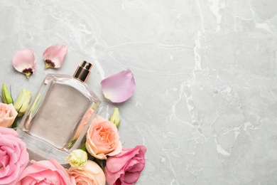 Photo of Flat lay composition with bottle of perfume and fresh flowers on light grey marble background, space for text