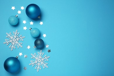 Photo of Christmas balls, decorative snowflakes and confetti on light blue background, flat lay. Space for text