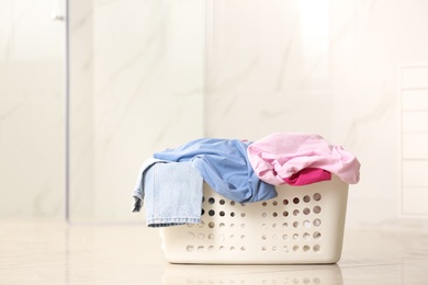 Photo of Laundry basket with dirty clothes on light background. Space for text