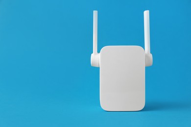 Photo of New modern Wi-Fi repeater on blue background, space for text