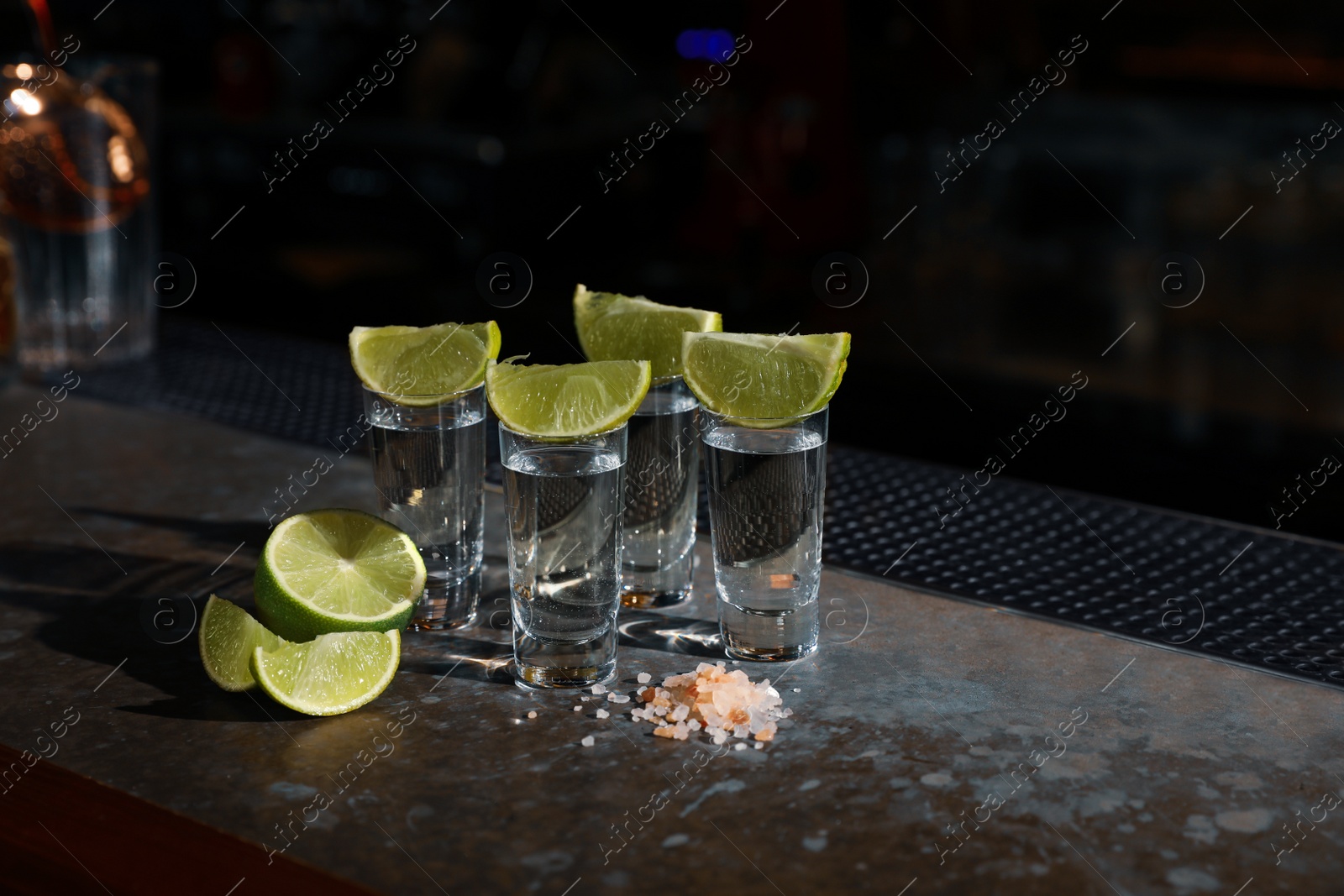 Photo of Mexican Tequila shots, lime slices and salt on bar counter