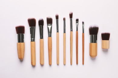 Photo of Different makeup brushes on white background, flat lay