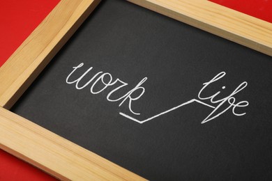 Photo of Chalkboard with words Work and Life on red background, closeup. Balance concept