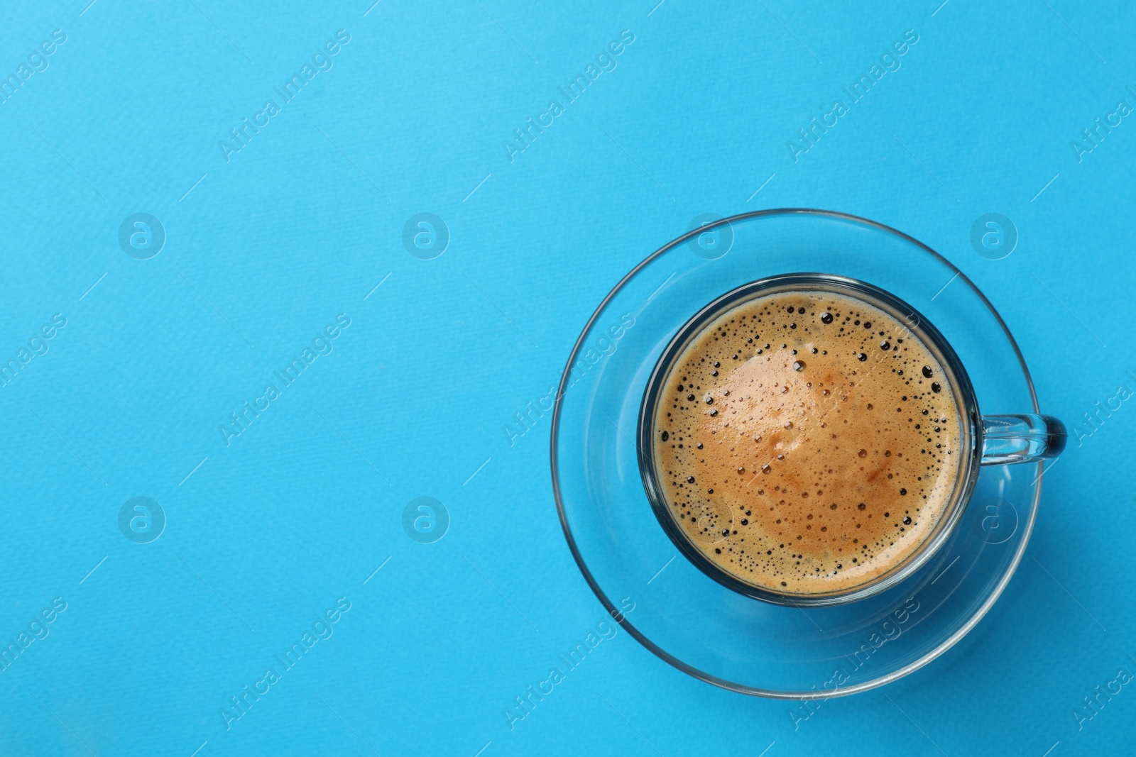 Photo of Fresh coffee in cup on light blue background, top view. Space for text