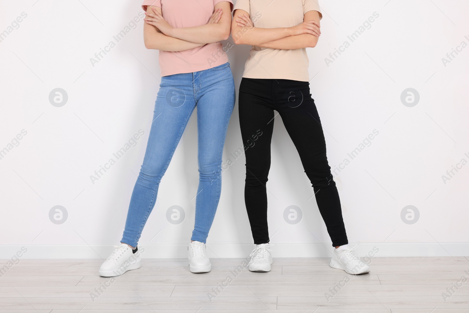 Photo of Women in stylish jeans near white wall, closeup