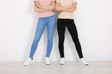 Photo of Women in stylish jeans near white wall, closeup