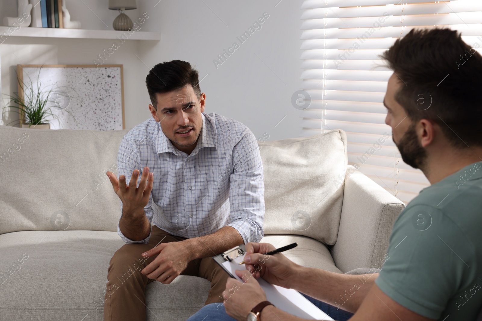 Photo of Unhappy man having session with his therapist indoors