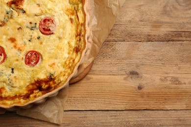 Delicious quiche with cheese and tomatoes on wooden table, top view. Space for text