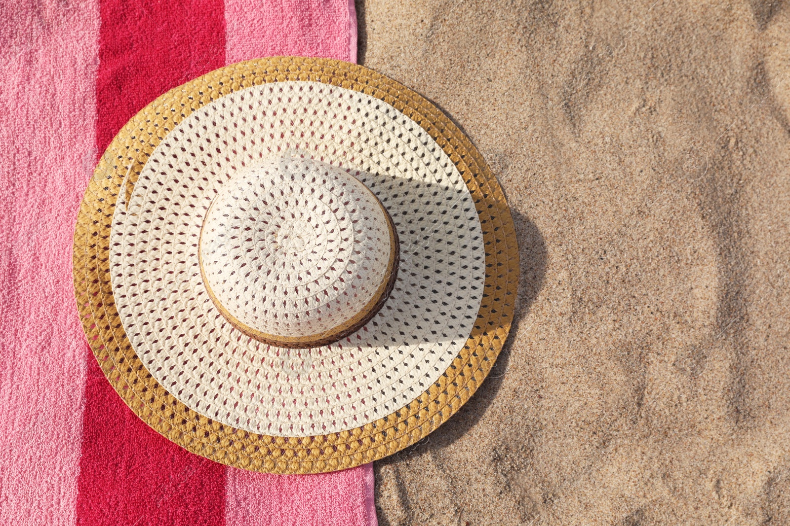 Photo of Beach towel and straw hat on sand, flat lay. Space for text