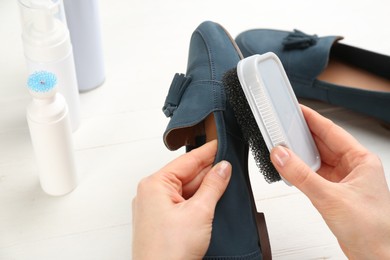 Woman taking care of stylish shoe at white table, above view