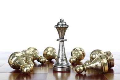 Photo of Silver queen among fallen golden pawns on wooden chess board against white background