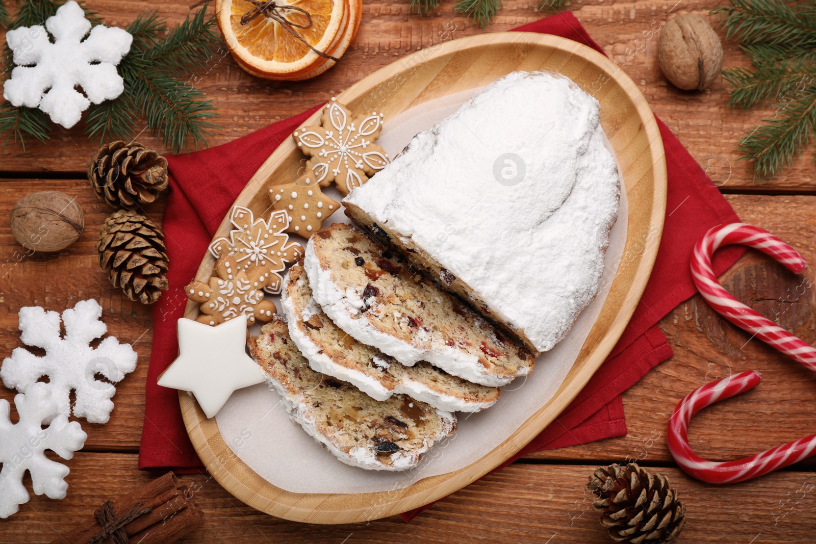 Photo of Traditional Christmas Stollen with icing sugar on wooden table, flat lay