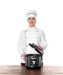 Female chef with modern multi cooker at table against white background