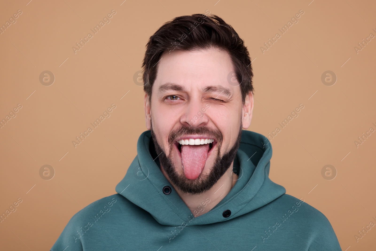 Photo of Happy man showing his tongue on beige background