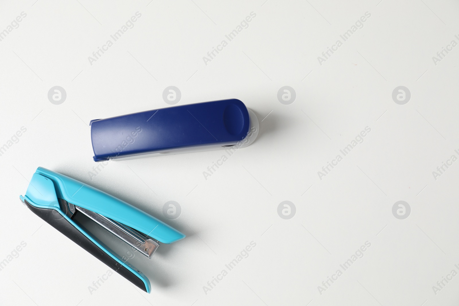 Photo of Color stapler on white table, flat lay. Space for text