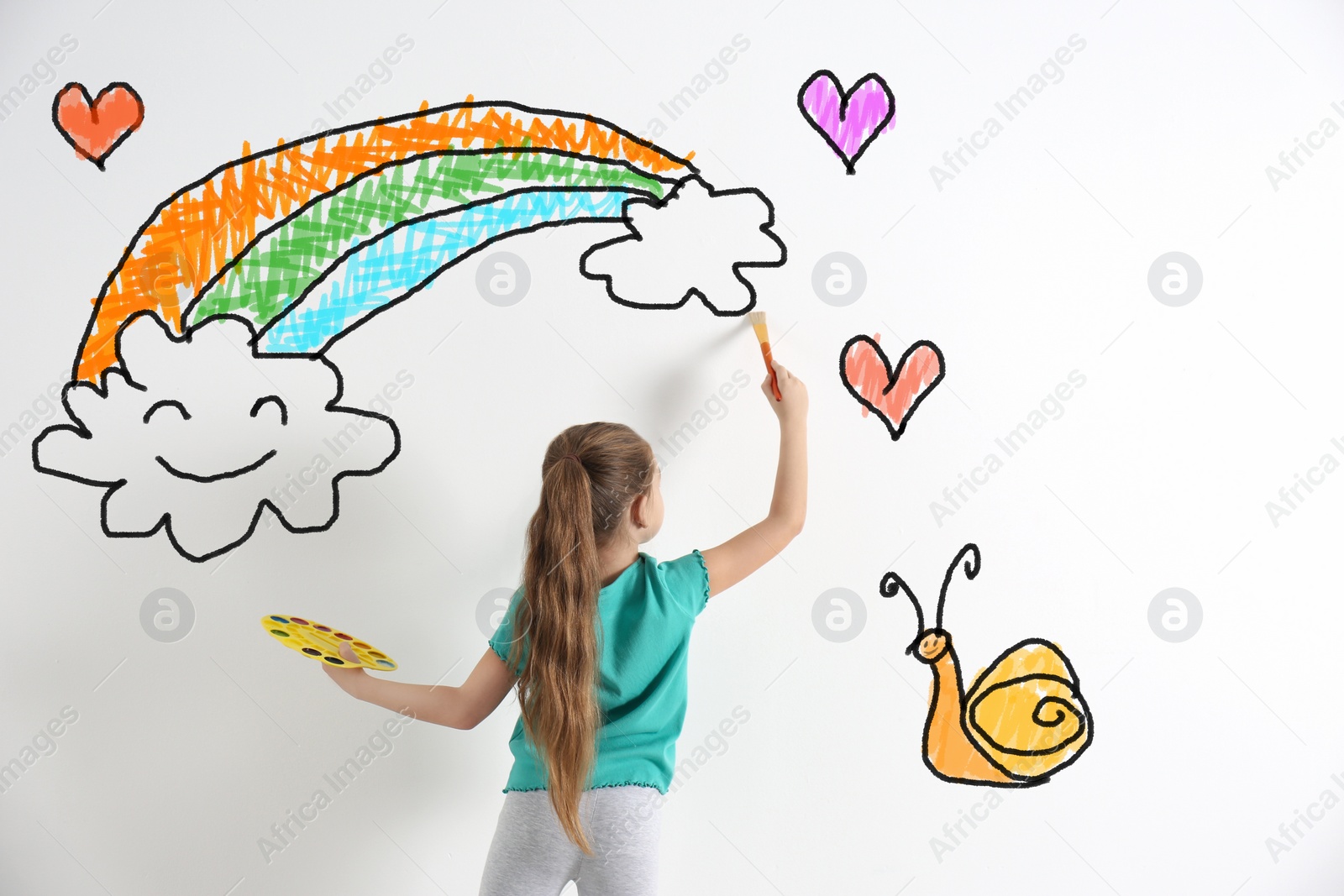 Image of Cute child drawing rainbow and clouds on white wall indoors