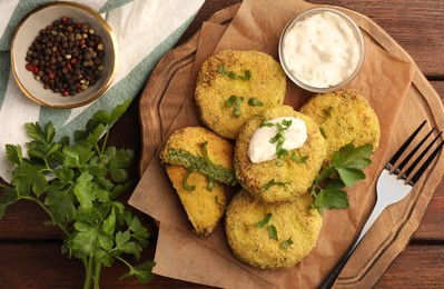 Photo of Tasty vegan cutlets served with sauce and ingredients on wooden table, flat lay