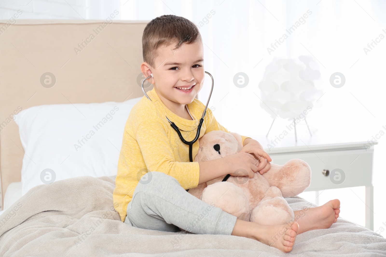 Photo of Cute child playing doctor with stuffed toy at hospital