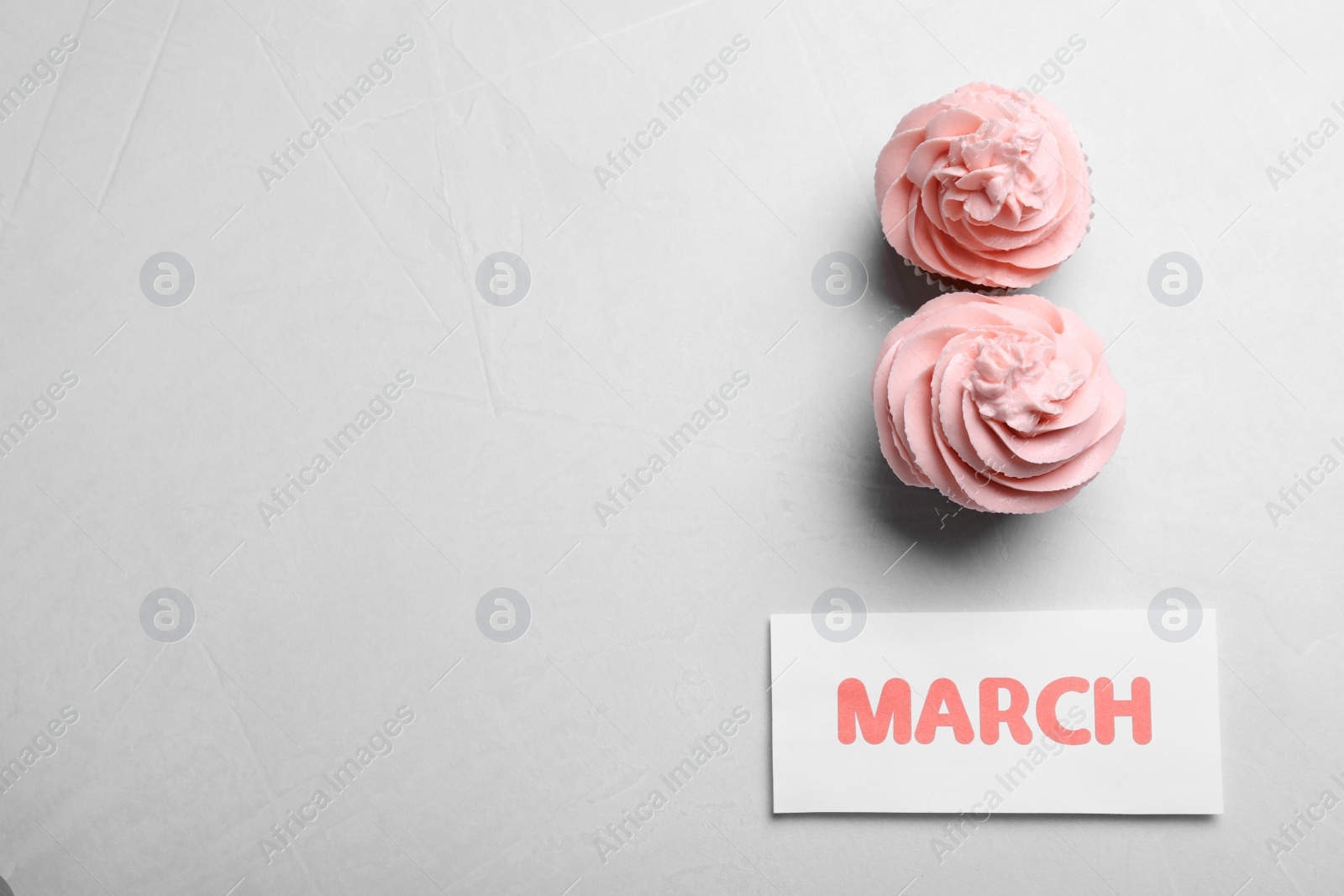 Photo of 8 March greeting card design with cupcakes and space for text on light grey background, flat lay. International Women's day