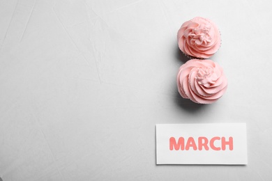 Photo of 8 March greeting card design with cupcakes and space for text on light grey background, flat lay. International Women's day