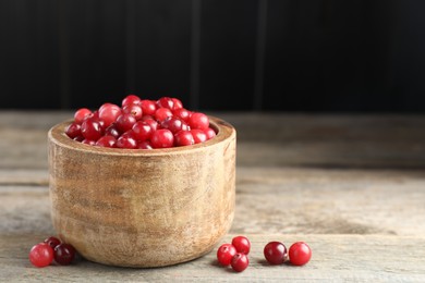 Photo of Cranberries in bowl on wooden table, space for text