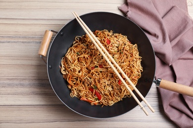 Wok pan of buckwheat noodles with chopsticks on table, top view