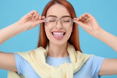 Happy woman showing her tongue on light blue background