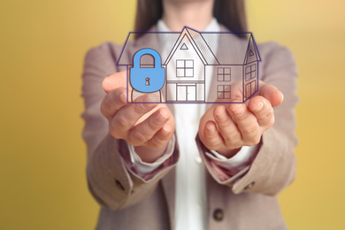 Home security concept. Woman holding house on yellow background, closeup