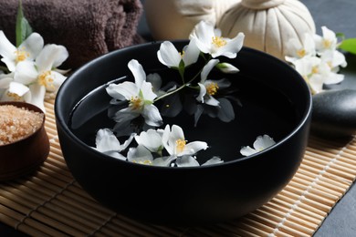 Photo of Beautiful spa composition with jasmine essential oil and fresh flowers on table, closeup