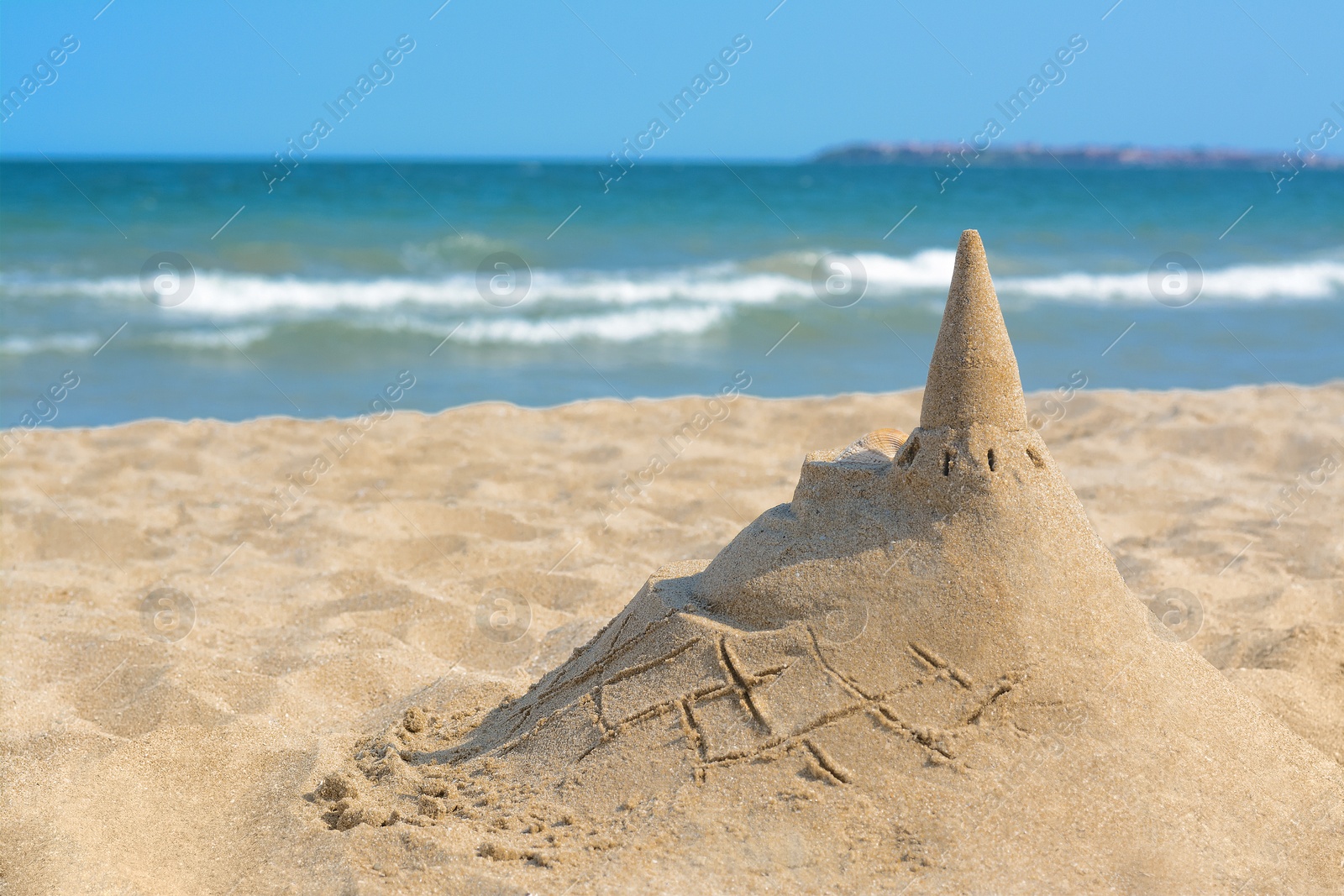 Photo of Beach with sand castle near sea on sunny day. Space for text