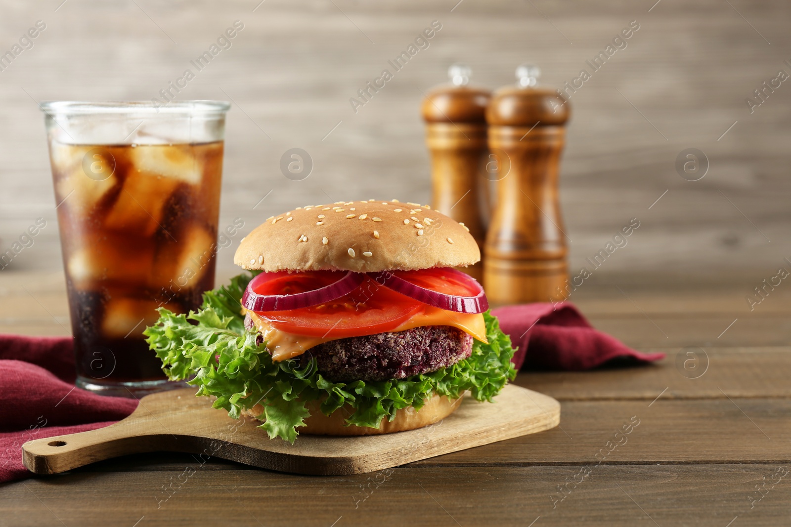 Photo of Tasty vegetarian burger with beet patty served on wooden table. Space for text