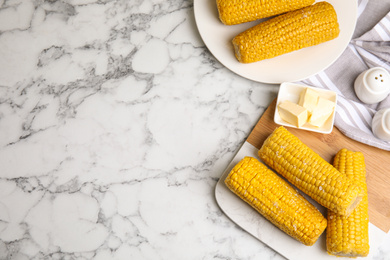 Photo of Delicious boiled corn served on white marble table, flat lay. Space for text