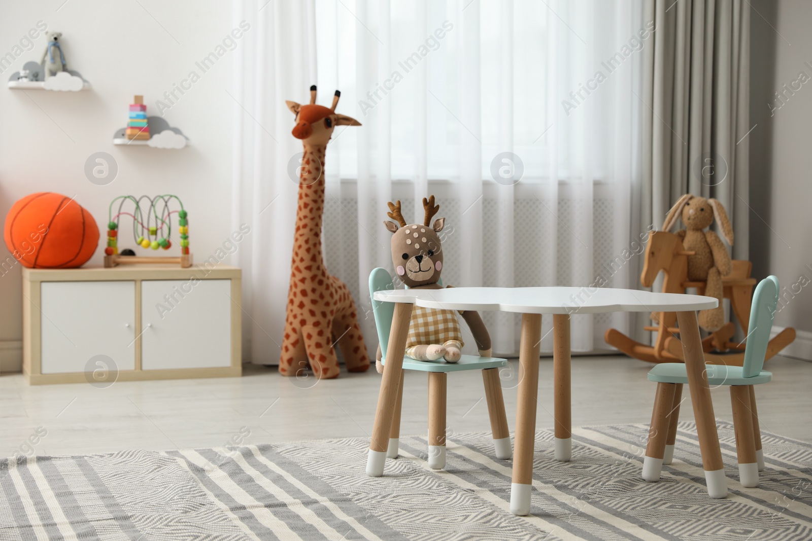 Photo of Child's room interior with stylish table, chairs and toys