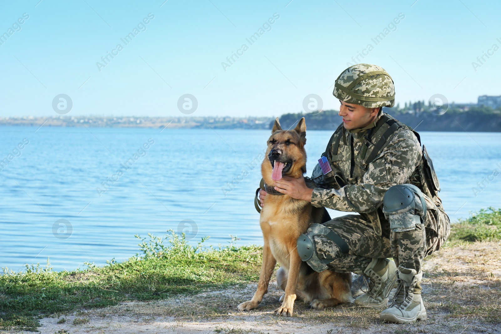 Photo of Man in military uniform with German shepherd dog near river, space for text