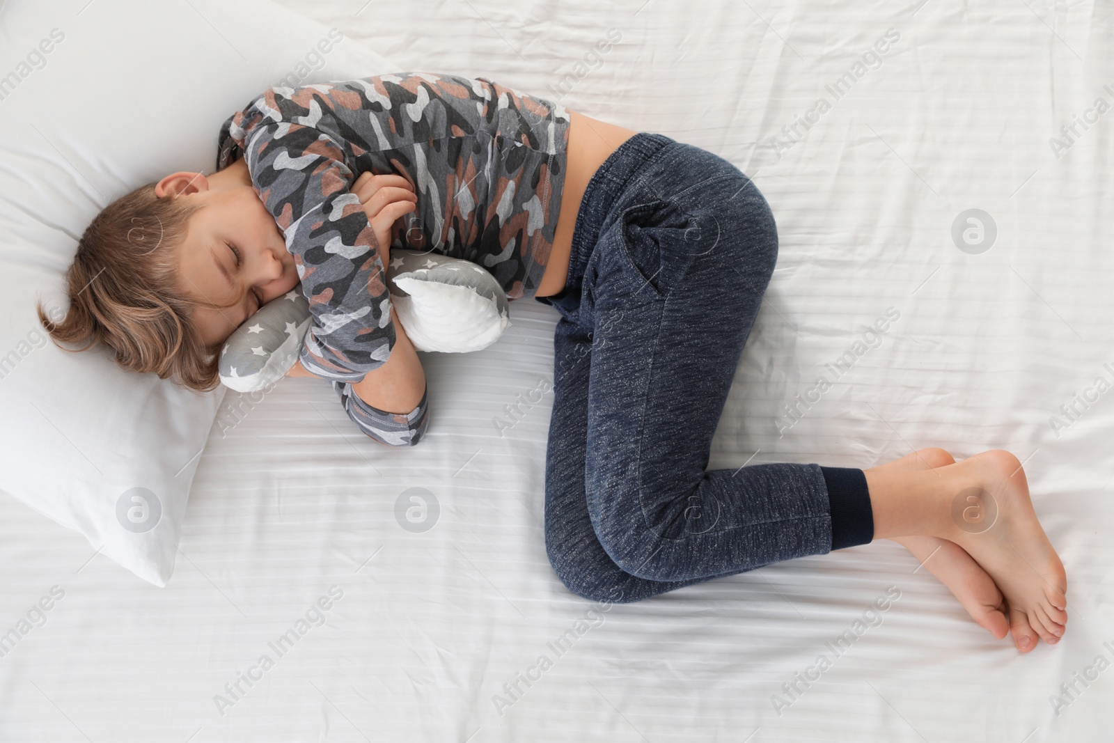 Photo of Cute boy with toy sleeping on bed, above view