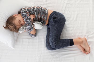 Photo of Cute boy with toy sleeping on bed, above view
