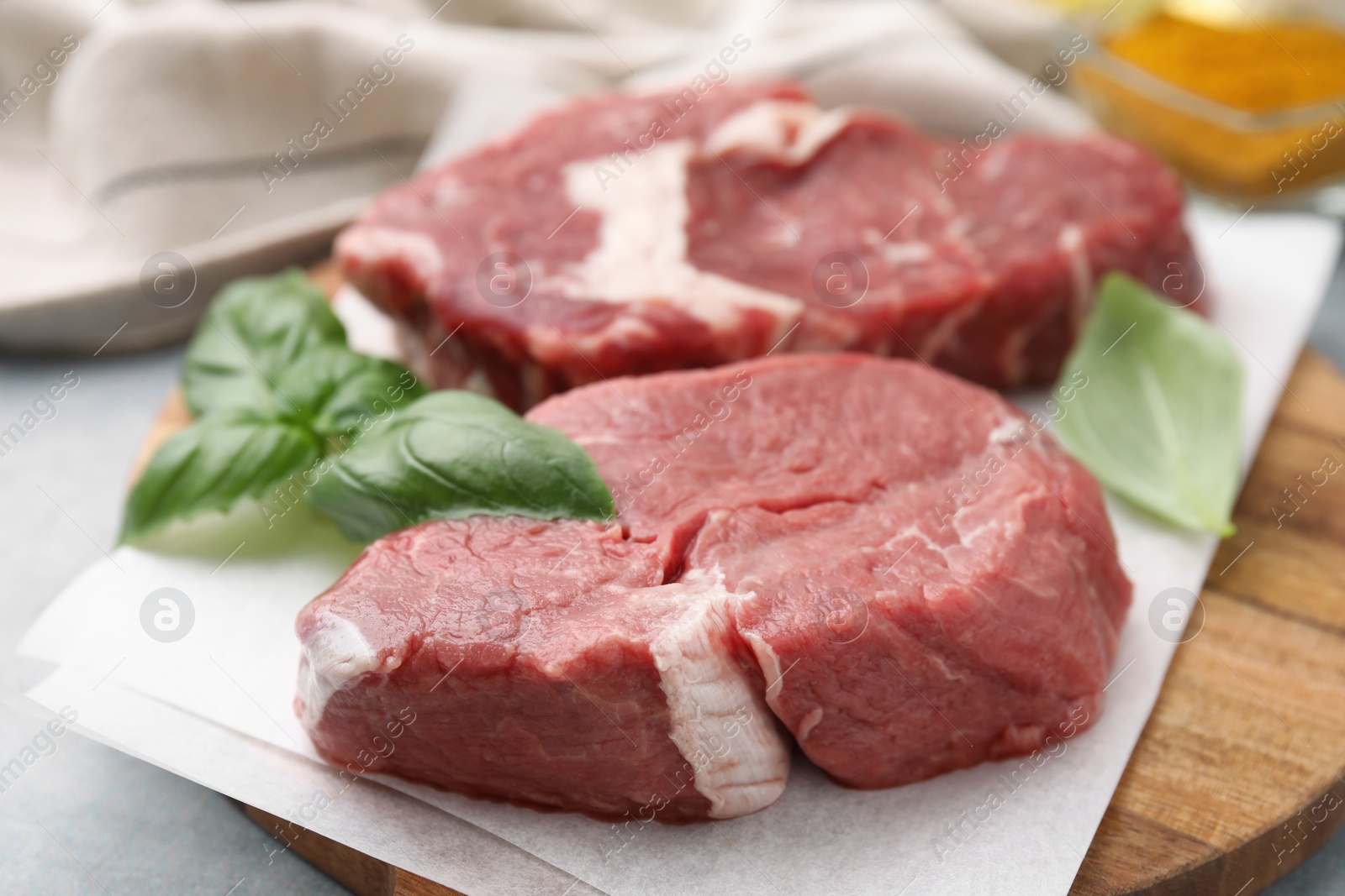 Photo of Cut fresh beef meat with basil leaves on wooden board, closeup